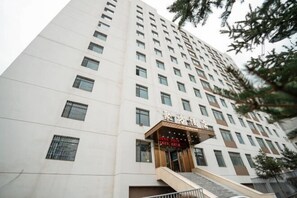 A tall, modern building with a prominent entrance featuring a staircase and a sign. - Xining Jufang Hotel (No.1 Vocational School Branch) (Xining)