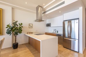 Een moderne keuken met een centraal eiland, roestvrijstalen apparatuur en een potplant.