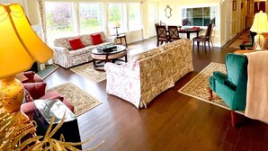 A spacious living room with a sofa, armchairs, and a dining table.