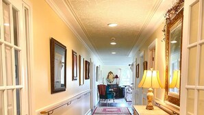 A hallway with patterned rugs, a mirror, and a lamp.