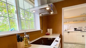 A modern kitchen with a large window, white cabinetry, and a built-in oven.