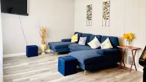 A living room with a sectional sofa, a small side table, and a wall-mounted TV.