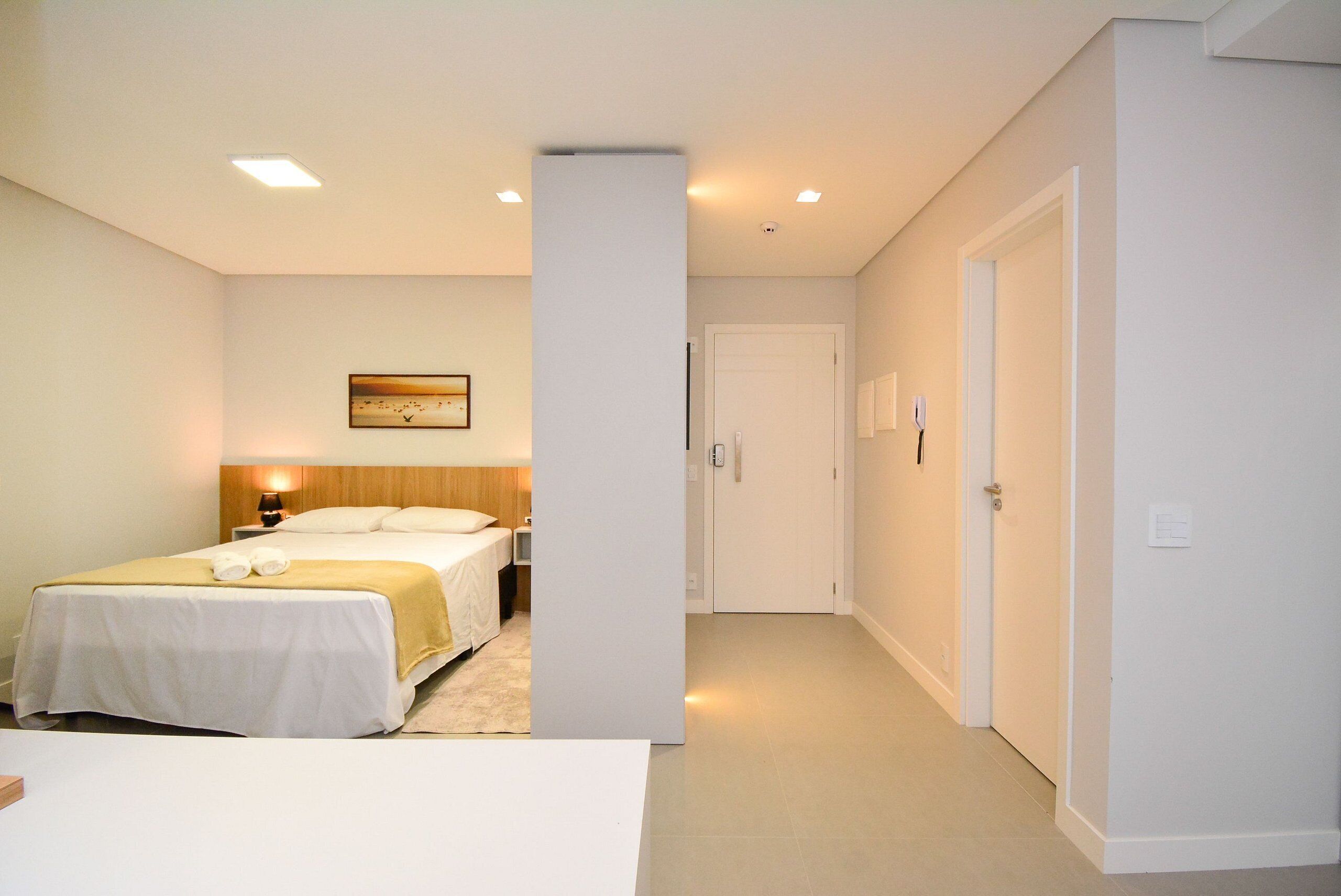 Een hotelkamer met een bed, nachtkastje, lamp en een schilderij aan de muur.