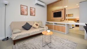 A modern living room with a sofa, a coffee table, and a TV mounted on a wooden panel. - Sunset Lagoa  (Florianopolis)