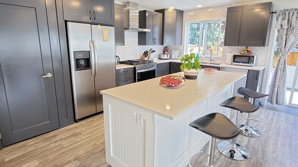 A modern kitchen with a central island, stainless steel appliances, and a wooden floor. - Homey Place in Sechelt , close to town and beaches (Sechelt)