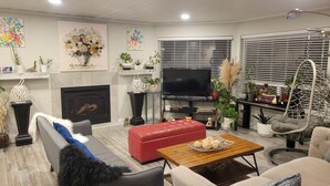 A modern living room with a fireplace, comfortable seating, a flat-screen TV, and various decorative items. - Homey Place in Sechelt , close to town and beaches (Sechelt)
