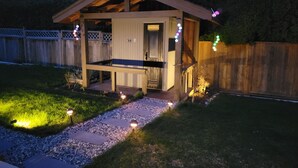 A small wooden cabin with a sauna sign, surrounded by a wooden fence, gravel path, and string lights. - Homey Place in Sechelt , close to town and beaches (Sechelt)