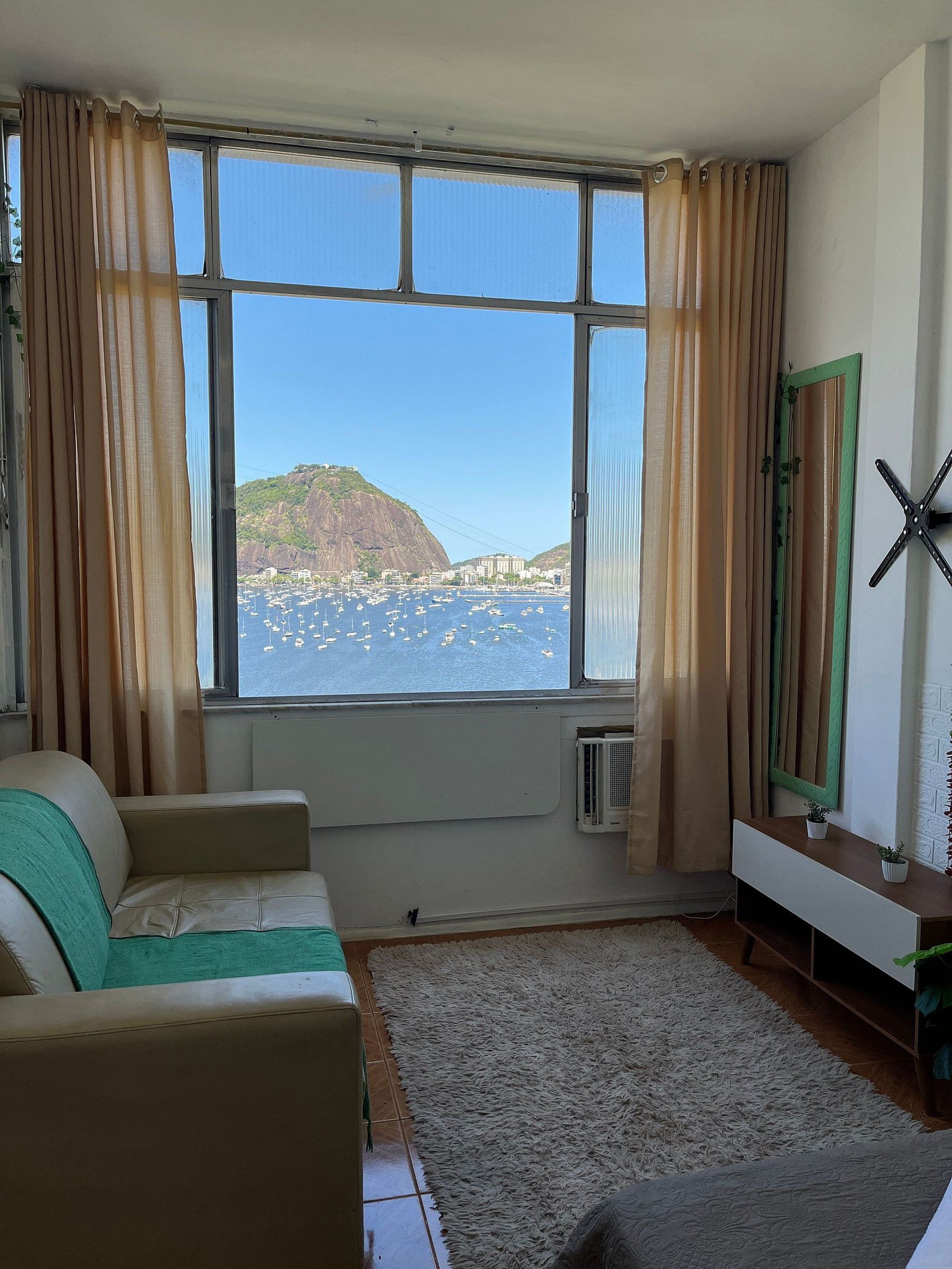 A room with a large window, a sofa, a radiator, and a mirror.