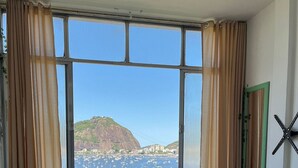 Une pièce avec une grande fenêtre, un canapé, un radiateur et un miroir.
