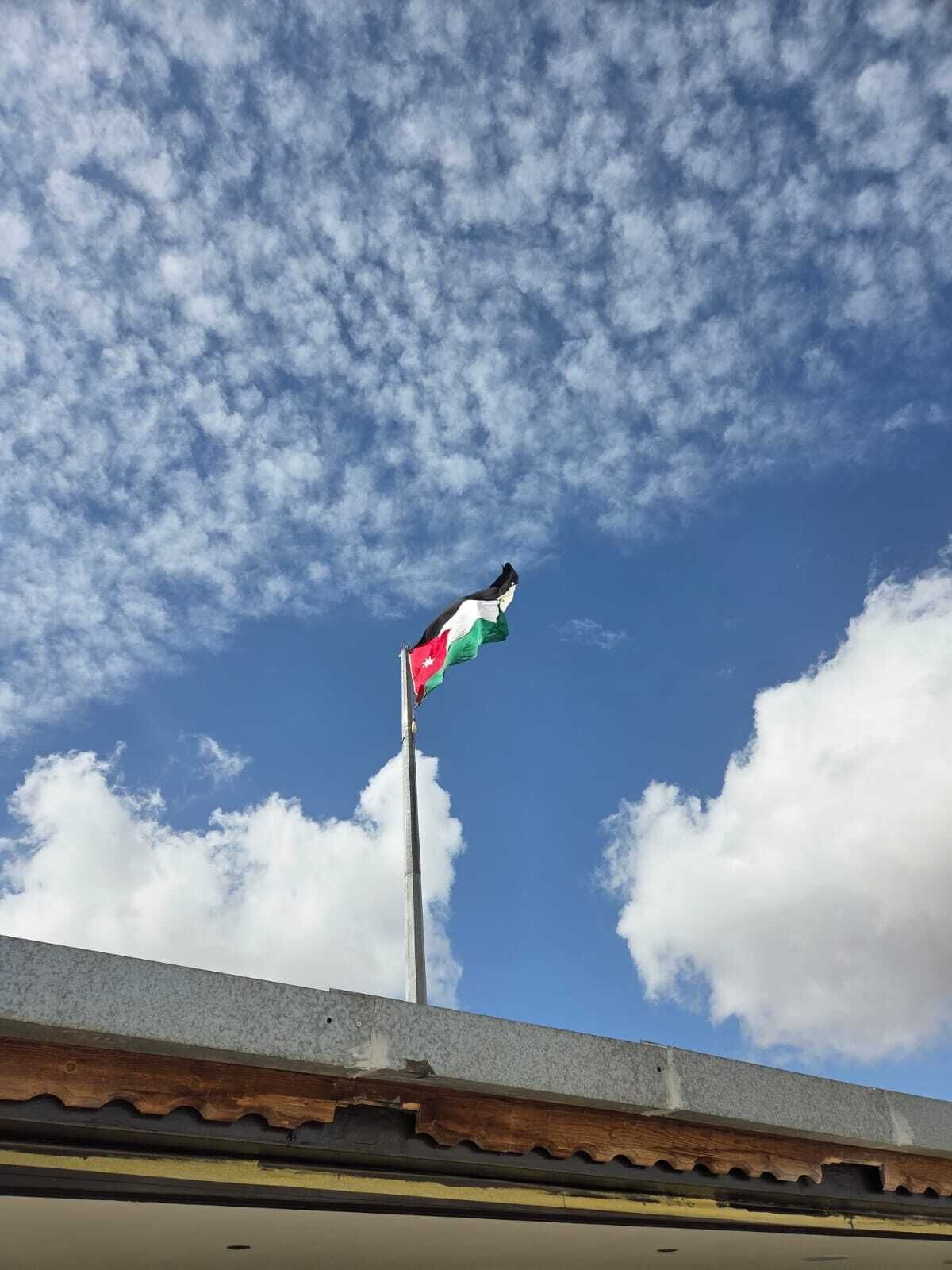 Ein Fahnenmast mit einer Flagge vor einem teils bewölkten Himmel.