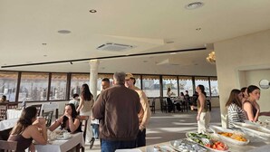 Um restaurante amplo com tetos altos e grandes janelas, oferecendo vista para a paisagem urbana.