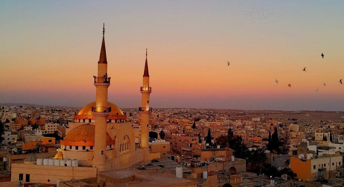 Una mezquita con dos minaretes y una cúpula, rodeada de una zona urbana densamente poblada.
