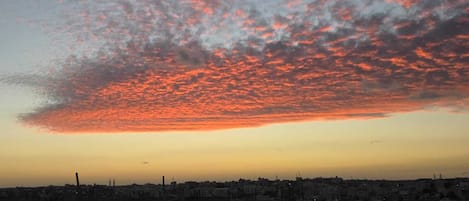 A sunset over a cityscape with a bridge in the foreground.