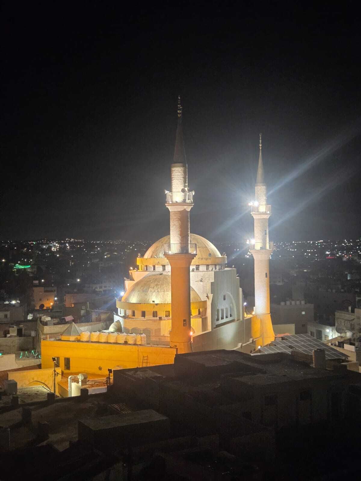 A mosque with two minarets and a large dome, surrounded by urban buildings.