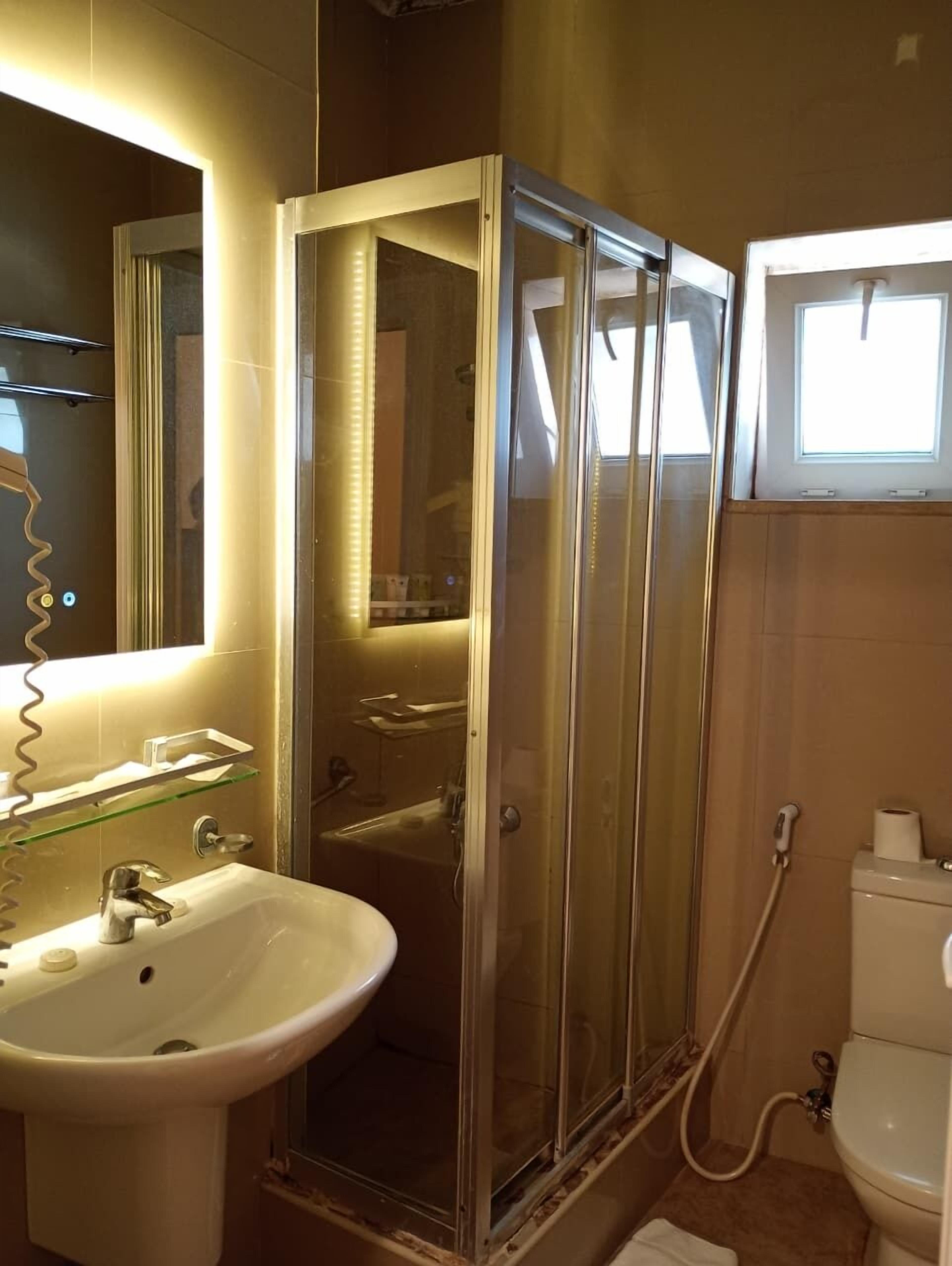 Un baño con ducha de vidrio, lavabo e inodoro.