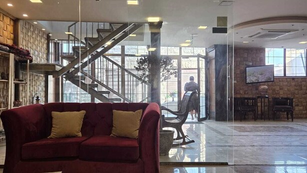 Um hall amplo com um sofá vermelho, uma escadaria e entrada de vidro.