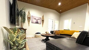 A living room with a black leather sofa, a coffee table, a TV, and decorative wall art.