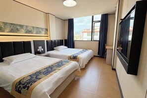 Une chambre d’hôtel avec deux lits, une grande fenêtre avec des rideaux et un tableau au mur.