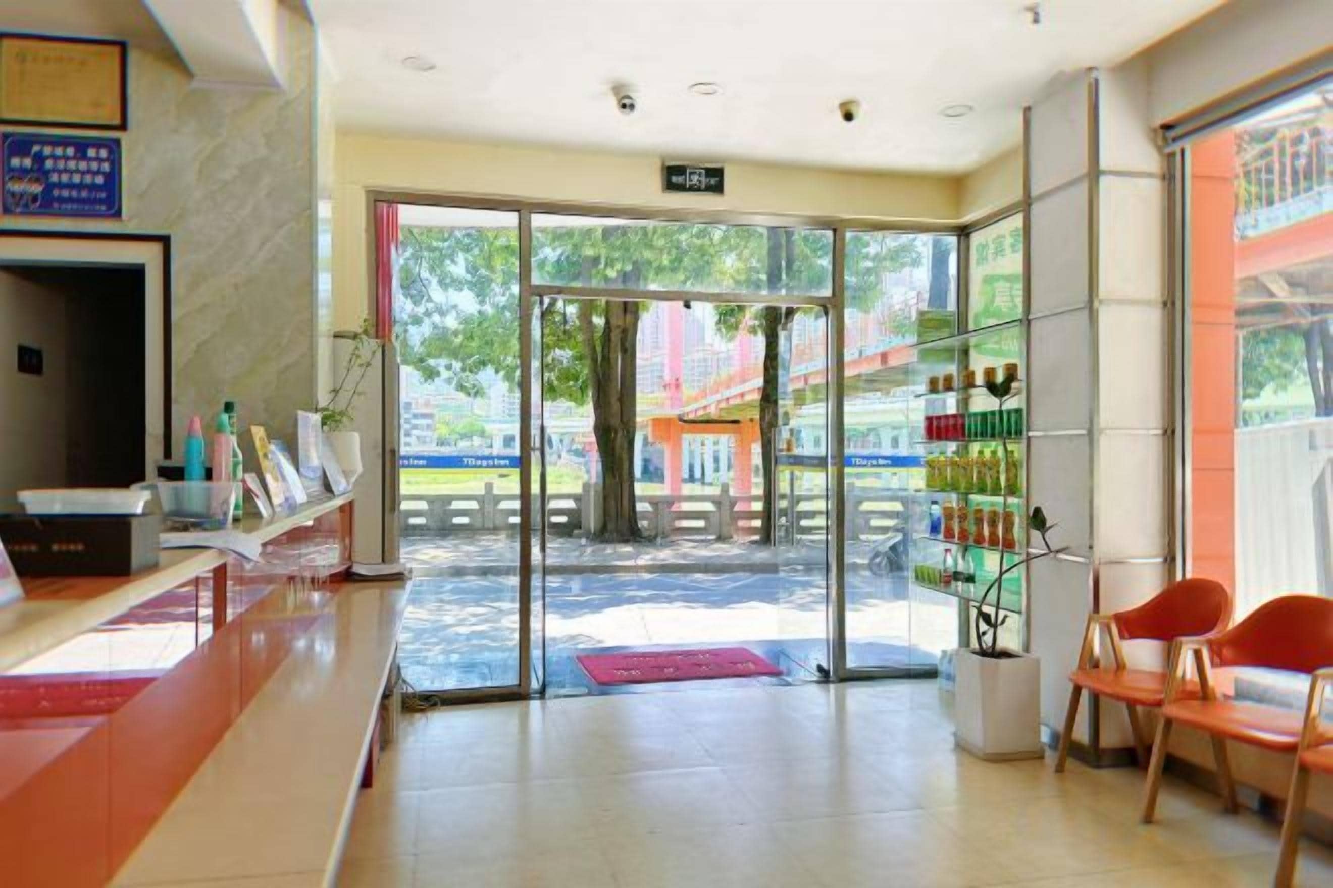 Un espace d’accueil comprenant un comptoir, une entrée avec une porte vitrée et un coin salon avec des chaises.
