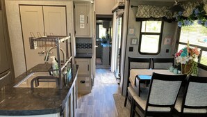 A compact RV interior with a kitchenette, dining area, and a small living space. - Charming 2-bedroom RV with WiFi and AC in peaceful Silverhill Alabama (Silverhill)
