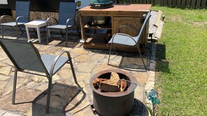 An outdoor patio with stone flooring, a fire pit, and a wooden table with chairs. - Charming 2-bedroom RV with WiFi and AC in peaceful Silverhill Alabama (Silverhill)