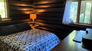 Habitació de cabana de fusta amb un llit, una taula i una làmpada.
