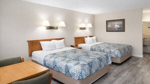 Una habitación de hotel con dos camas, un escritorio y un cuadro en la pared.