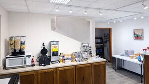 Una kitchenette con microondas, plancha para waffles, cafetera y dispensadores de snacks.