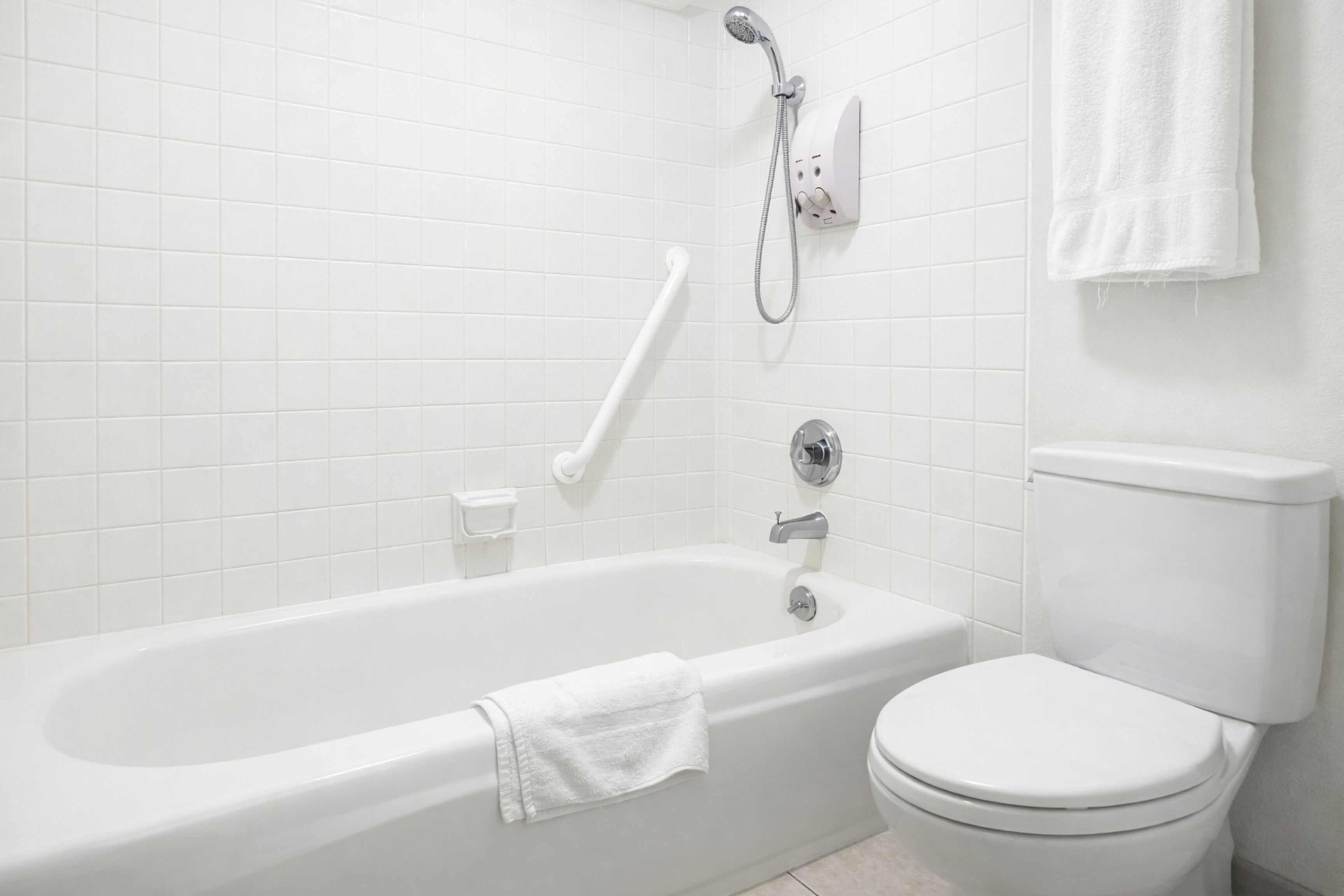 A bathroom with a white bathtub, a toilet, and a shower unit.