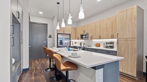 Une cuisine moderne dotée d’un îlot central, de meubles en bois et de luminaires suspendus.