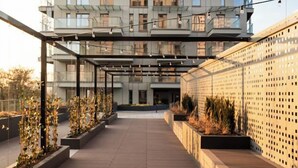 A modern building with multiple balconies and a covered outdoor area with planters. - Apartament Tower by Kairos Apartments (Katowice)