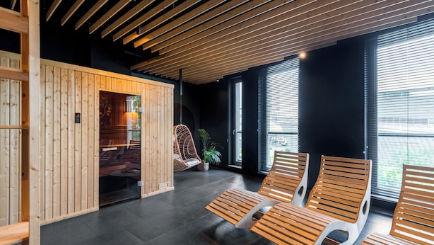 A modern interior with wooden panel walls, a hanging chair, and a seating area with benches. - Apartament Tower by Kairos Apartments (Katowice)