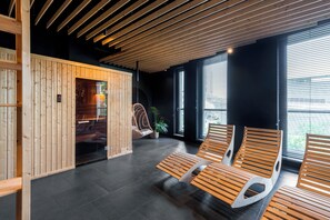 A modern interior with wooden panel walls, a hanging chair, and a seating area with benches. - Apartament Tower by Kairos Apartments (Katowice)