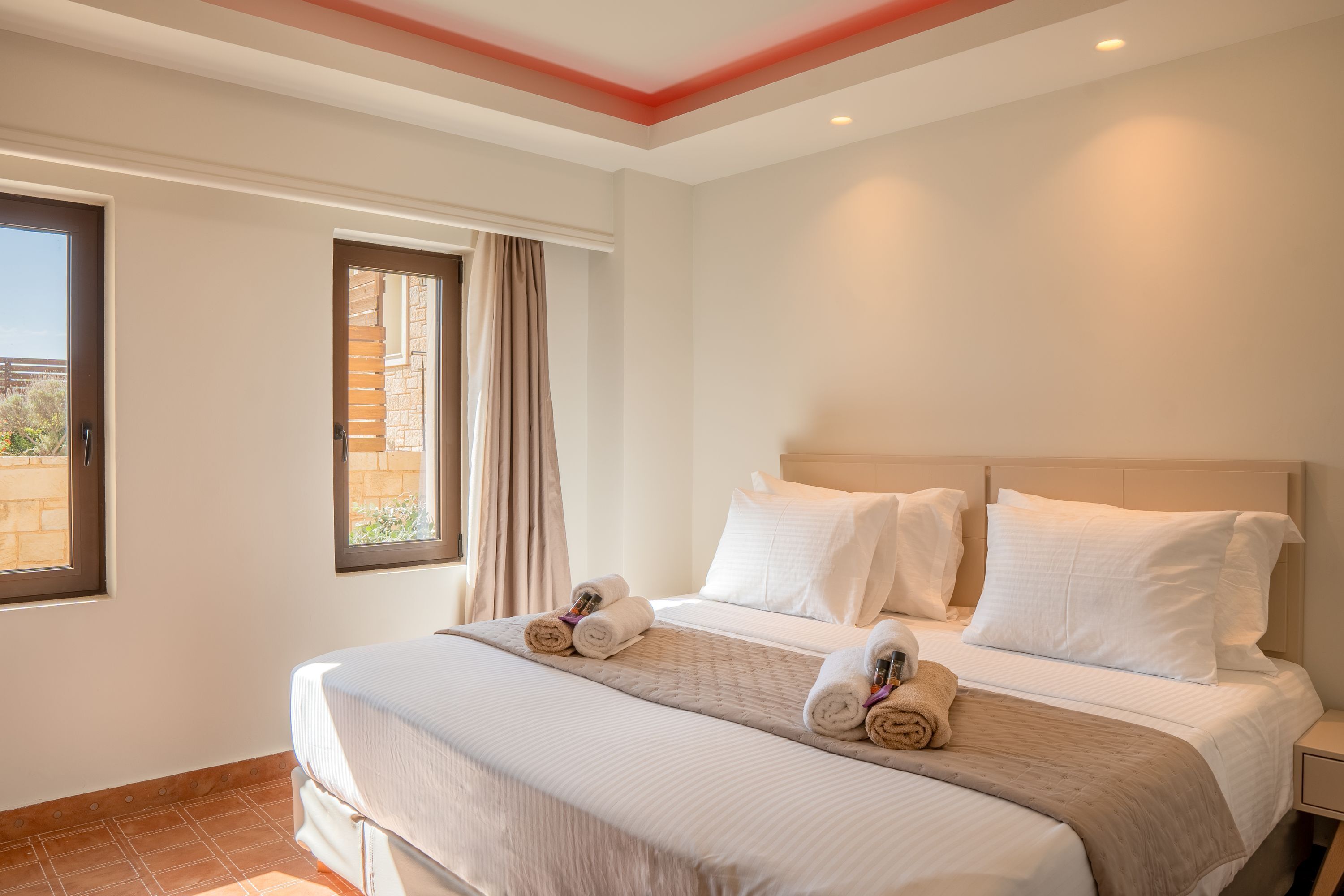 A hotel room with a large bed, two bedside tables, a window with curtains, and a view of the outside.