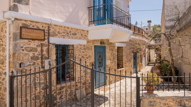 A traditional stone house with a balcony, a gate, and a sign indicating it is a traditional Cretan house. - Traditional Cretan House (Faistos)