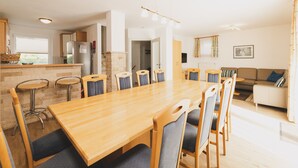 Una cocina moderna con encimera de madera, refrigerador empotrado y comedor con una mesa grande y sillas.