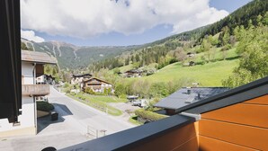 Un pueblo de montaña con casas de madera tradicionales, un camino despejado y colinas verdes exuberantes.
