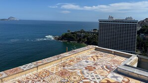 Vista costera con techo estampado, un edificio con la leyenda "Sheraton" y una isla distante.
