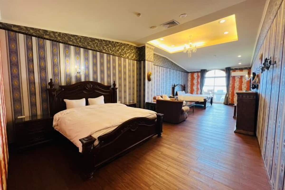 Habitación de hotel con una cama grande, un escritorio, una silla y un tocador.
