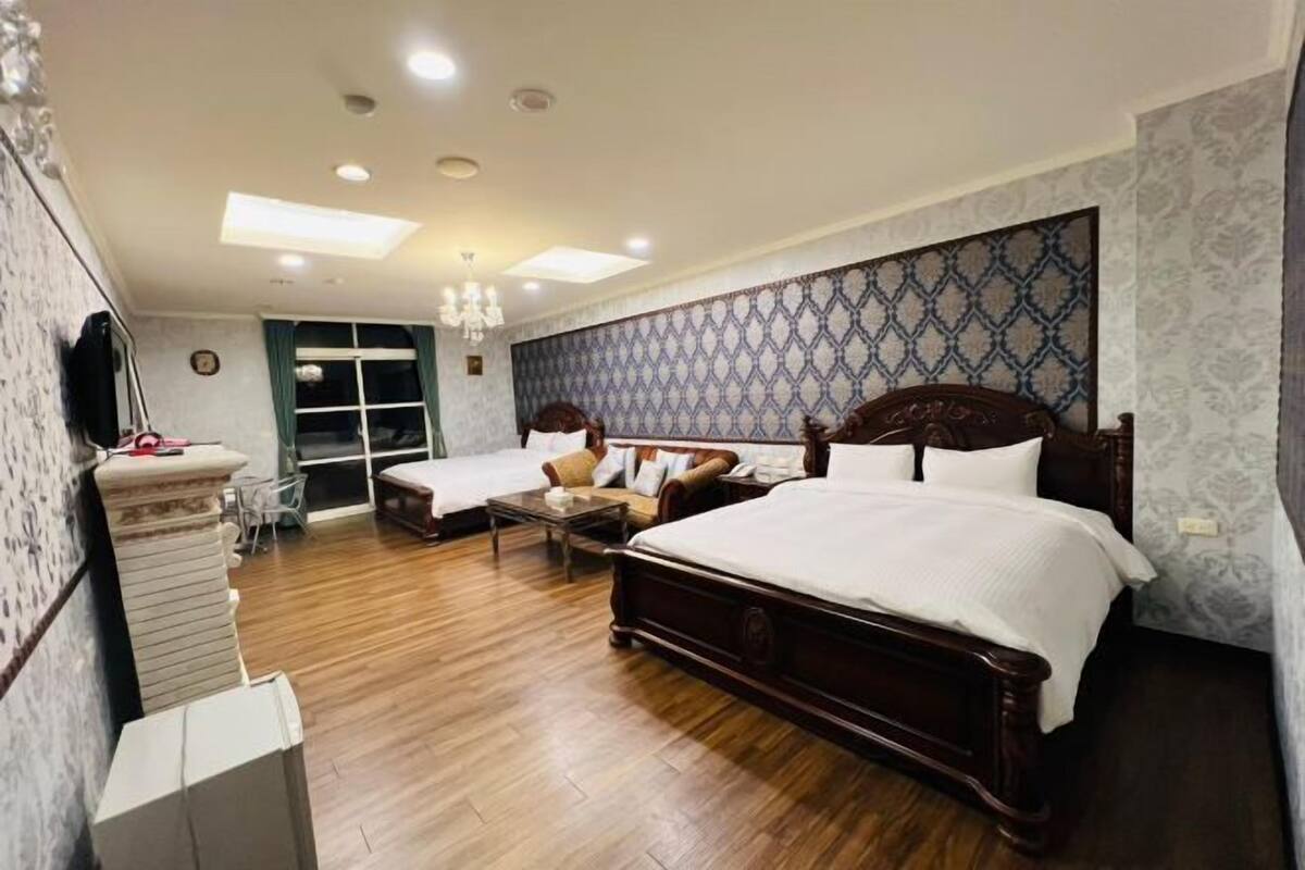 Un dormitorio con una cama grande, dos camas más pequeñas, un aparador, un espejo y una araña.