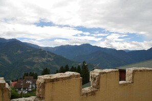 A mountainous landscape with a building featuring stone walls and a small window. - Huis Ten Bosch (Nantou)