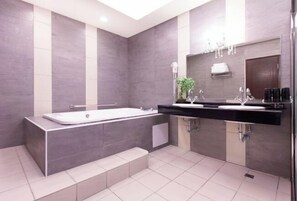 Un baño moderno con bañera, lavamanos y espejo.