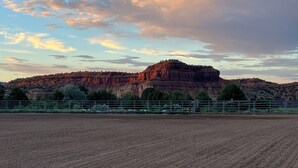 A fenced field with a large rock formation in the background.