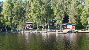 Una cabaña junto al lago con un muelle, rodeada de un bosque denso.