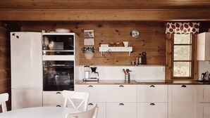 Una cocina con armarios blancos, un refrigerador Bosch, un horno Siemens y una cafetera.