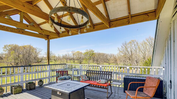 Une terrasse couverte avec un banc en bois, une table et une chaise.
