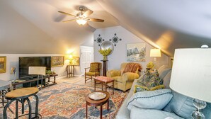 Un salon chaleureux avec un ventilateur de plafond, un grand téléviseur à écran plat, un canapé, une table basse et un tapis à motifs.