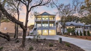 Une maison à deux étages avec un porche à l’avant, une allée et un jardin aménagé.