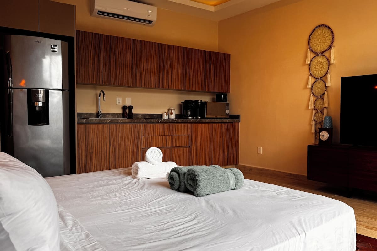 A hotel room with a bed, a minibar, a microwave, a coffee maker, and a flat-screen TV.