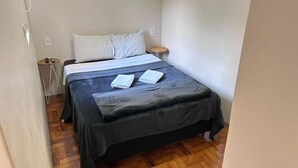A small, neatly arranged bedroom with a bed, bedside tables, and a wooden floor. - Soul Hostel 2 (Sao Paulo)